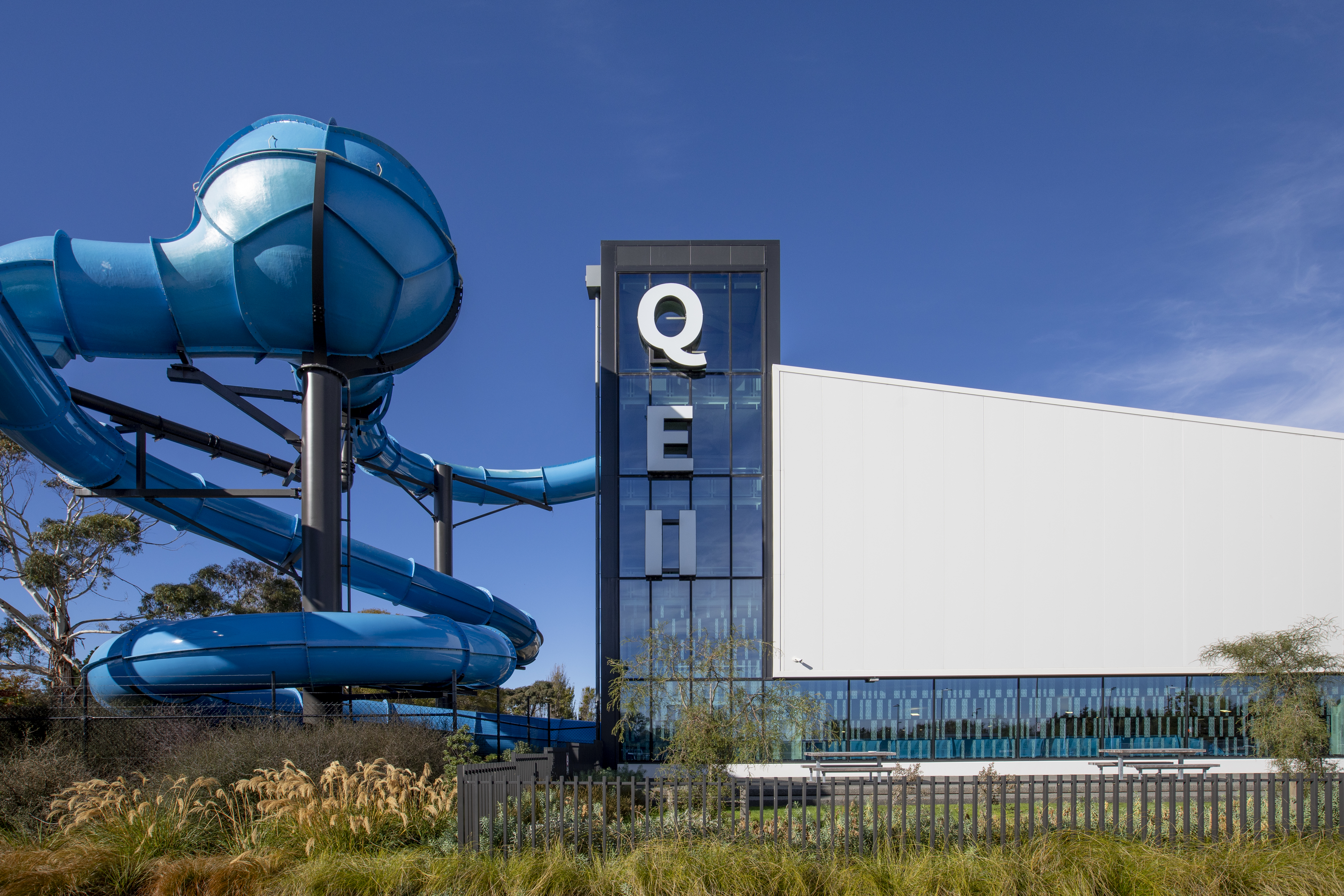 The outside of Taiora QEII Recreation and Sport centre with the blue hydroslide wrapping around the side. 