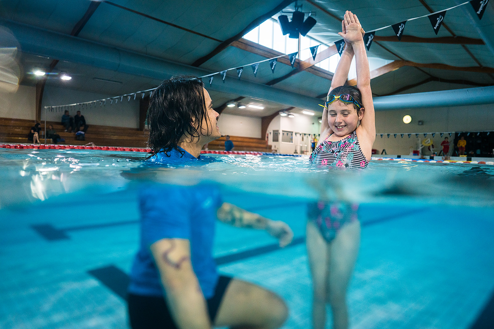 A male swim instructor helping a child practice their diving at Christchurch Recreation and Sport pool. 