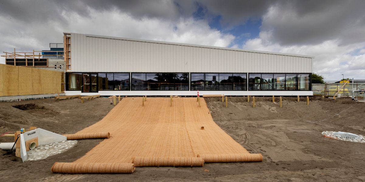 Large sheets of fabric being rolled onto the ground outside of Matatiki Recreation and Sport centre during construction.