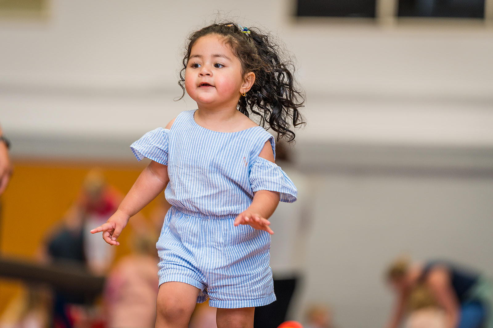 A smiling toddler running during a Tumbletimes class at Christchurch Recreation and Sport Centre.