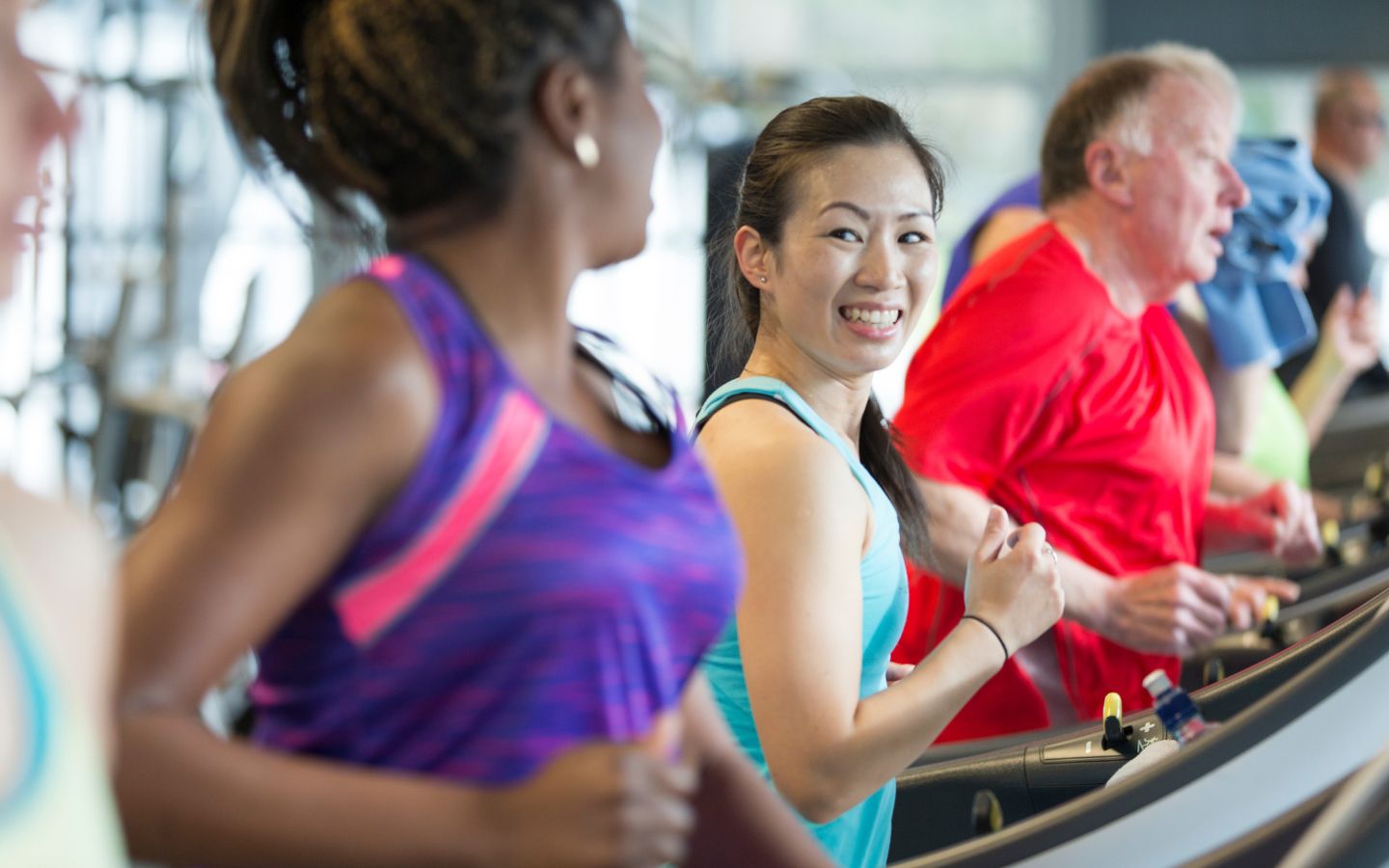 A row of smiling women running on treadmills. 