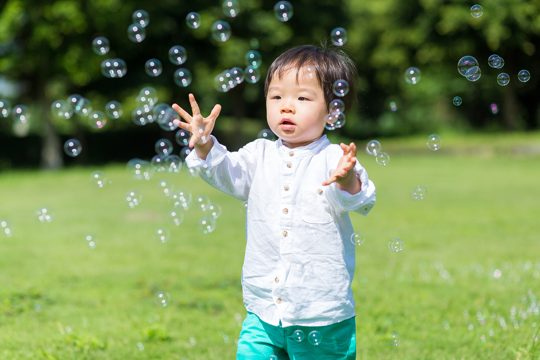 A little boy trying to catch bubbles. 