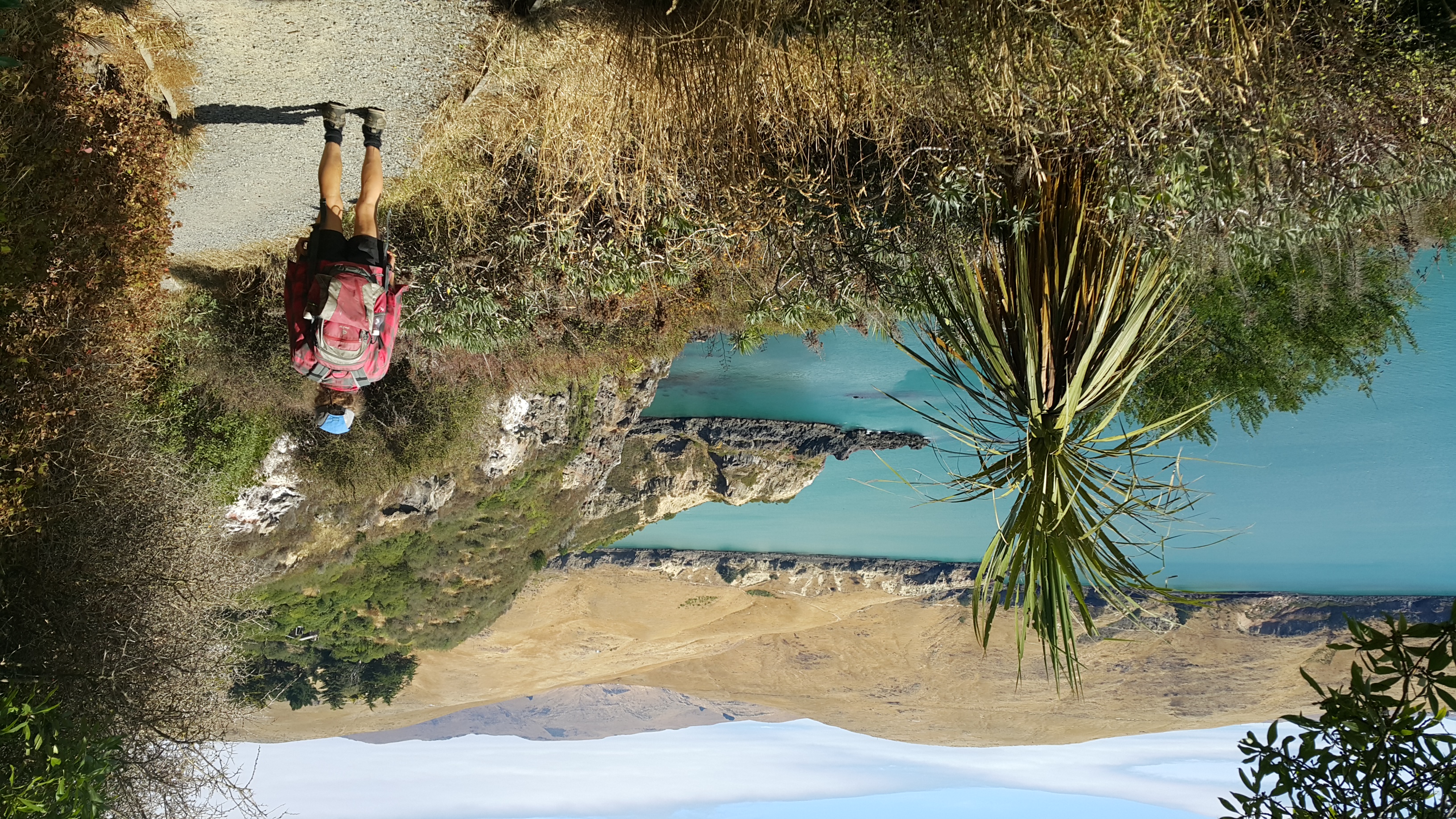 A person wearing a red backpack walking down the Taylors Mistake Track walking along the waterfront. 
