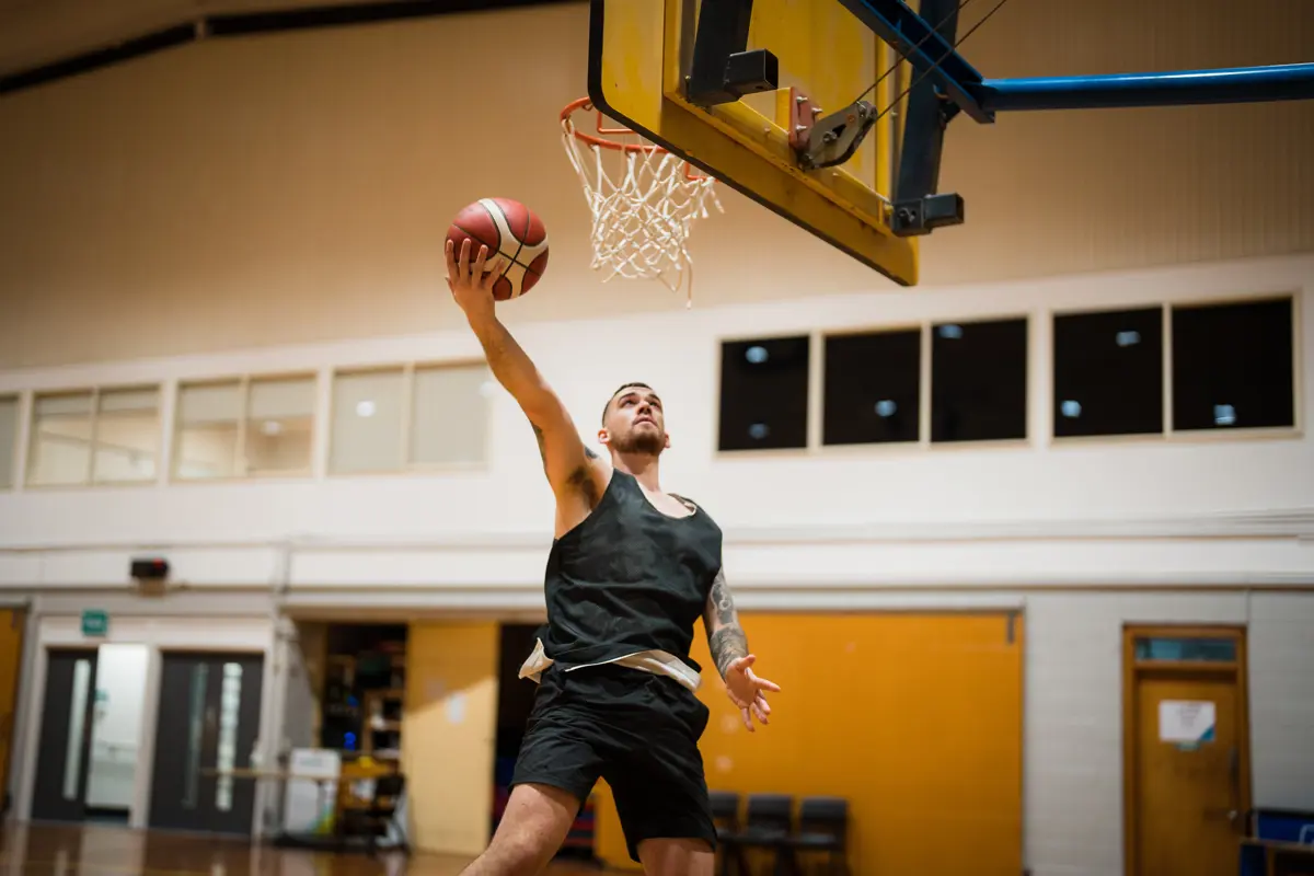 A man jumping to sink a basketball in a net at Christchurch Recreation and Sport centre.