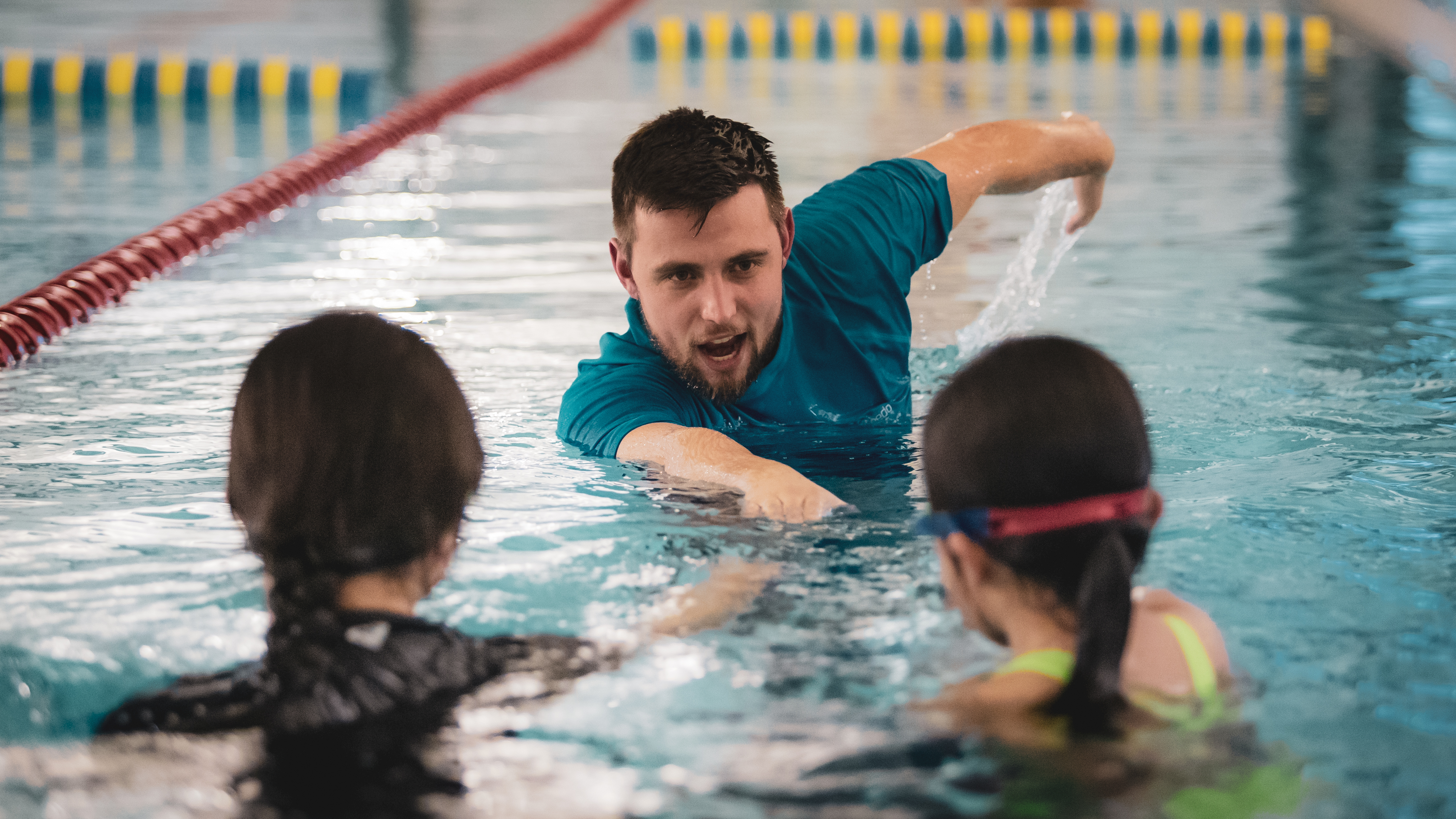 A male swim instructor demonstrating front stroke to two children at Christchurch Recreation and Sport.