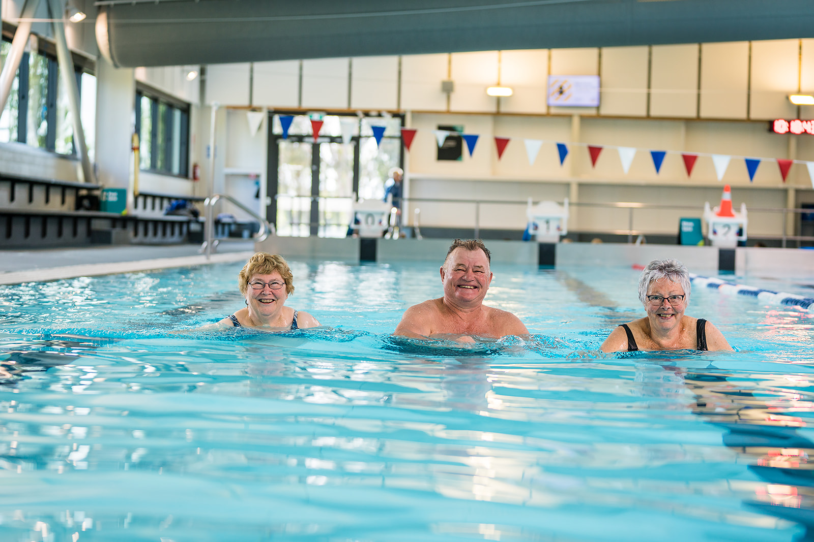 Two older women and an older man smiling standing in the pool at Christchurch Recreation and Sport pool. 