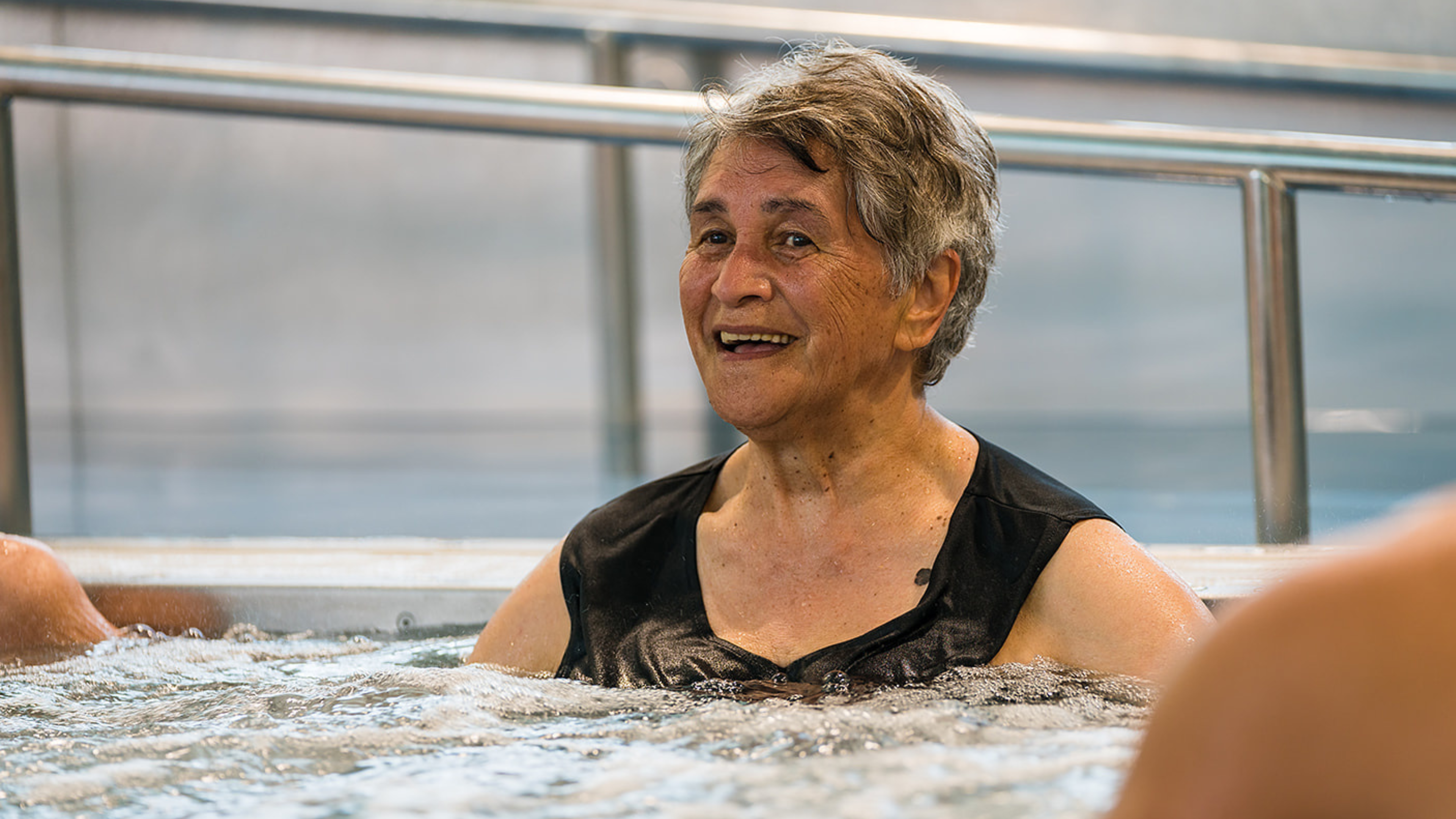 A smiling older woman enjoying the spa at Christchurch Recreation and Sport pool. 
